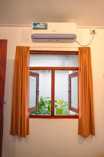 a television on top of a window with an orange curtain at CosyNsurf in Matara