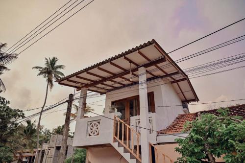 a house with a balcony and a palm tree at CosyNsurf in Matara