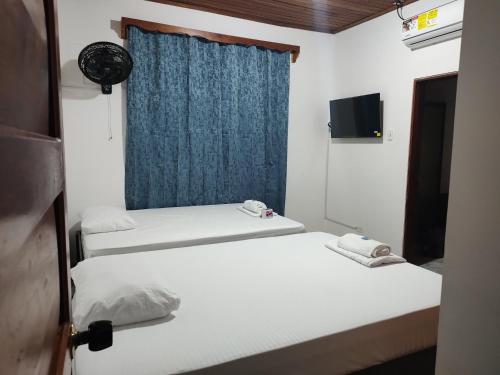 two beds in a room with a window and a television at El Jaguar Casa Hotel in Leticia