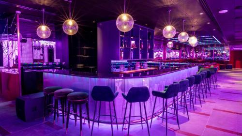 a nightclub with purple lighting and bar stools at voco Dubai Monaco, the Heart of Europe by IHG in Dubai