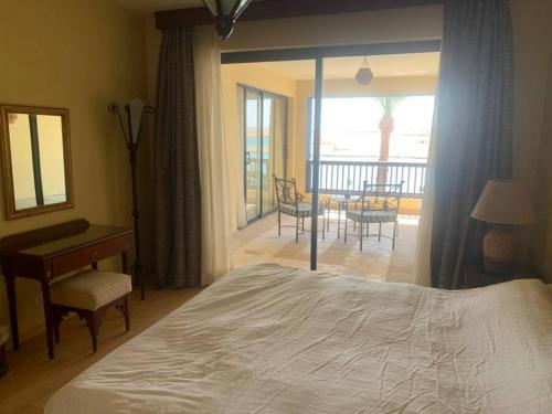 a bedroom with a bed and a desk and a balcony at Marina Bliss-Seaside Retreat in Marsa Alam
