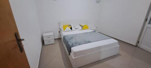 a white bedroom with a white bed with yellow pillows at Maravilha do Planalto in Assomada