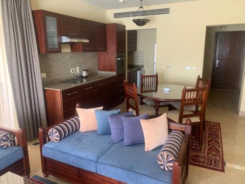 a living room with a blue couch and a kitchen at Marina Bliss-Seaside Retreat in Marsa Alam