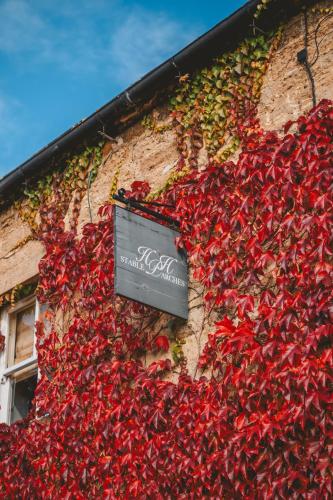 a building covered in red ivy with a sign on it at Stable Arches Boutique B&B at Hooton Pagnell Hall in Doncaster