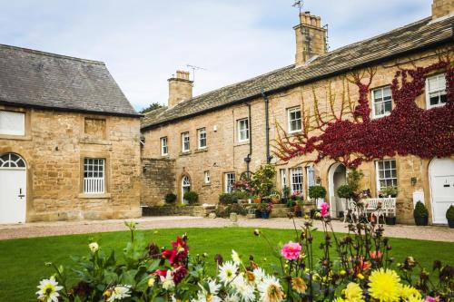 an old stone house with flowers in front of it at Stable Arches Boutique B&B at Hooton Pagnell Hall in Doncaster