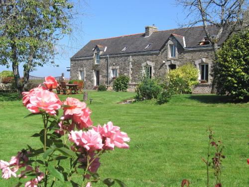 une maison en pierre avec des fleurs roses devant elle dans l'établissement Chambres d'hôtes - Au Domaine des Camélias, à Pluméliau