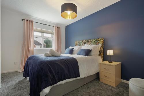 a bedroom with a bed with blue walls and a window at St Abbs - Beautiful Home, EV, parking, garden in Hull