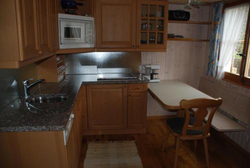 cocina con armarios de madera, fregadero y encimera en Ferienstudio Betula, en Schwarzsee