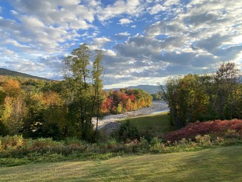 a river in the middle of a field with trees at COZY LOON MOUNTAIN ESCAPE - Free shuttle, Pool, Hot tub, River&Mnt Views in Lincoln