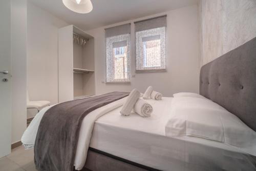 タオルミーナにあるFlower Taormina Apartmentの白いベッドルーム(大型ベッド1台、窓2つ付)