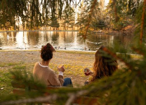 two women sitting on the grass near a lake at O Cuend'U Lac in Osséja
