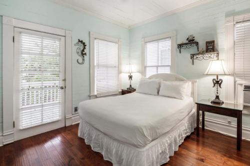 a bedroom with a white bed and two windows at Curry House - Room 1 in Key West