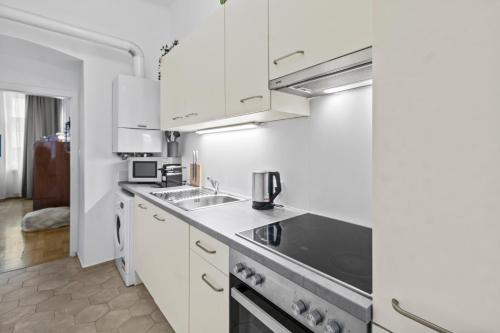 eine weiße Küche mit Spüle und Herd in der Unterkunft Spacious 2 Bedroom I 2 Minutes to Metro and Train Station in Wien
