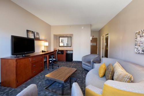 a living room with a couch and a flat screen tv at Courtyard by Marriott Dallas-Fort Worth/Bedford in Bedford