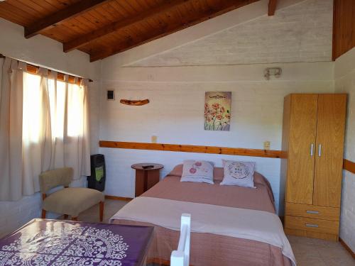 ein Schlafzimmer mit einem Bett und einem Stuhl in der Unterkunft Nahucar in El Bolsón
