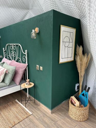 a room with a green wall with a bed and a table at The Frog Glamping in Horezu