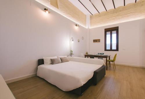 een witte slaapkamer met een groot bed en een tafel bij Miraflores 58 Apt - Private Parking Opt in Sevilla