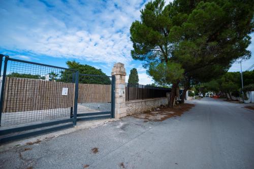 a fence next to a street with a tree at Villa Gianto pool & spa in Polignano a Mare