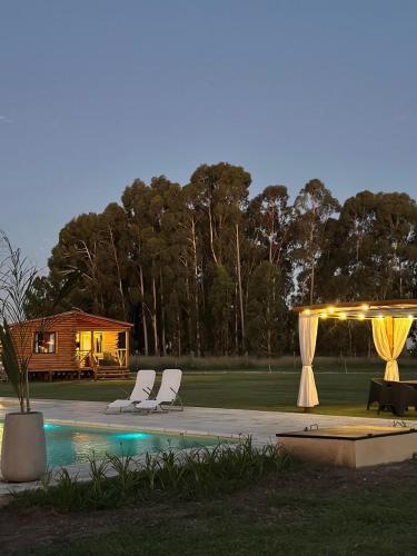 a couple of white chairs sitting next to a pool at Cabañas Laguna de los Sauces in Azul