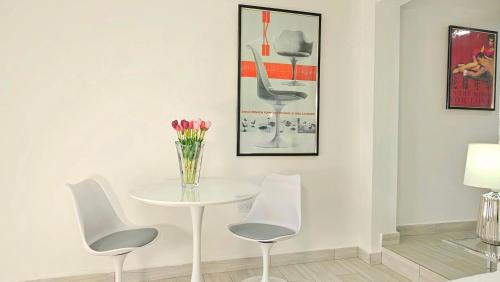 a white table with three chairs and a vase of flowers at Casa Reina by Villa Alejandro in Boquete