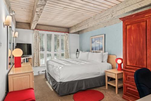 una camera da letto con un letto grande e una sedia rossa di Chateau Eau Claire Unit 1, Stylish Condo Overlooking the River, Walking Distance to Downtown ad Aspen