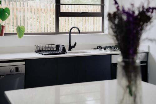 Heather Road Cottages في جورج: مطبخ مع حوض و مزهرية من الزهور