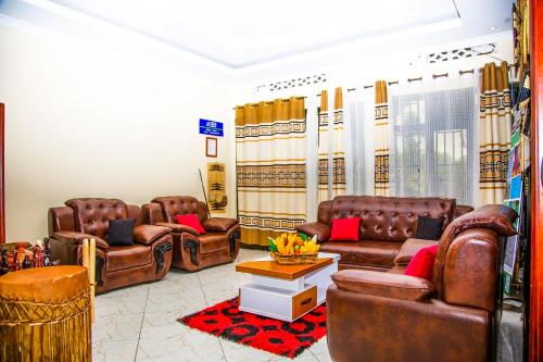 a living room with brown leather chairs and a table at Virunga Homestays in Ruhengeri