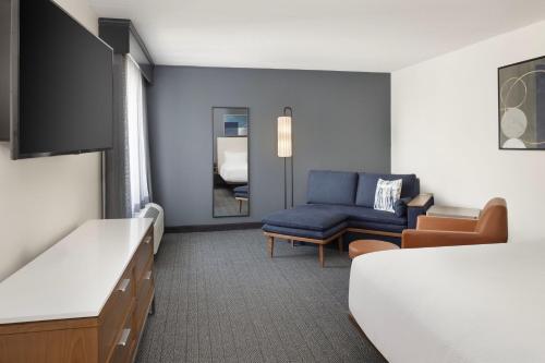 a hotel room with a bed and a blue couch at Courtyard Edison Woodbridge in Edison