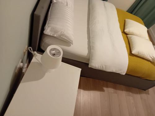 a bed with white pillows and a table with a alarm clock at City Apartment in Manchester