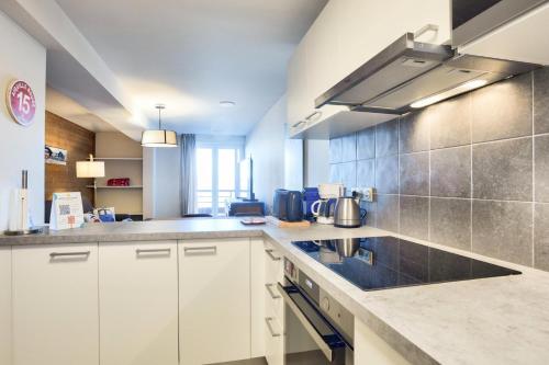 une cuisine avec des armoires blanches et un comptoir dans l'établissement Résidence les Chardons - maeva Home - Appartement 3 pièces 6 personnes vue montagne - Sélection MAE-2011, à Arc 1800