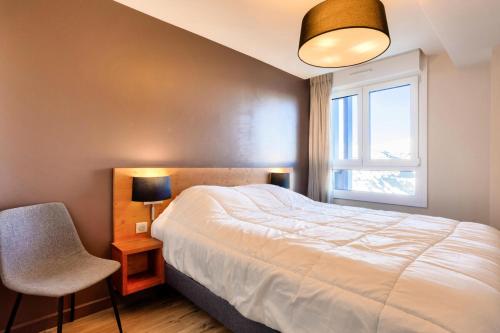 une chambre avec un lit, une chaise et une fenêtre dans l'établissement Résidence les Chardons - maeva Home - Appartement 3 pièces 6 personnes vue montagne - Sélection MAE-2011, à Arc 1800