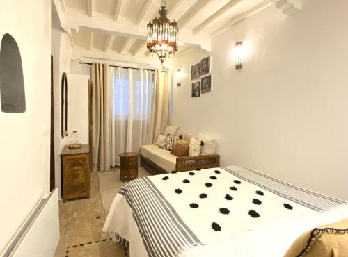a bedroom with a bed and a chandelier at Riad l'Ayel d'Essaouira in Essaouira