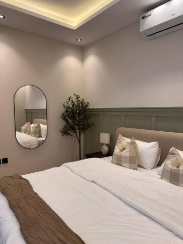 een slaapkamer met een groot wit bed en een spiegel bij غرفة على الطراز الريفي in Riyad