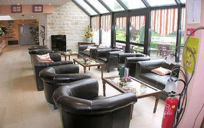 a living room with black leather couches and tables at Auberge De Bourgogne in Tonnerre