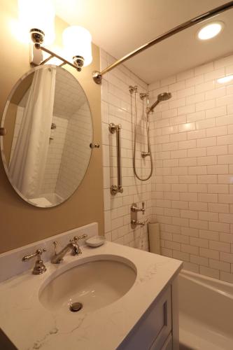 a bathroom with a sink and a mirror and a tub at Swift House Inn in Middlebury
