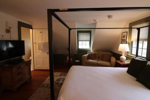 a bedroom with a canopy bed and a living room at Swift House Inn in Middlebury
