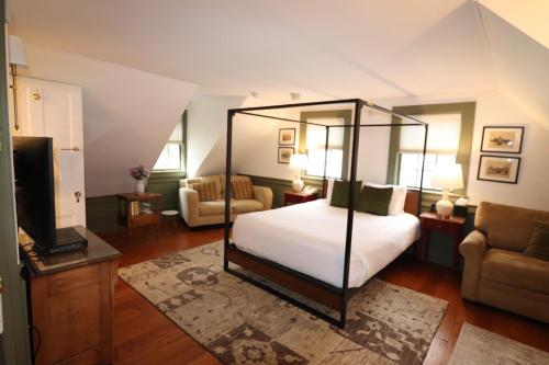 a bedroom with a canopy bed and a television at Swift House Inn in Middlebury