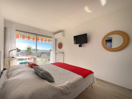 une chambre avec un lit avec un miroir et une fenêtre dans l'établissement Tanit charmant 3 pièces, grande terrasse, à Antibes