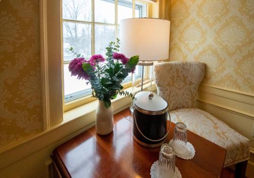 a vase of flowers on a table next to a window at Swift House Inn in Middlebury