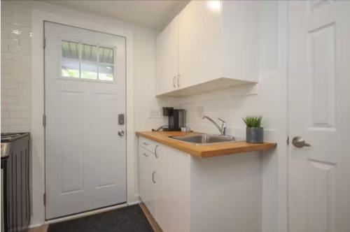 a white kitchen with a sink and a door at Montfort Hotel in Ottawa