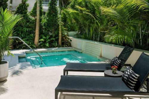 a swimming pool with two chairs and a bench next to it at Yellow Room at Grand Maloney in Key West