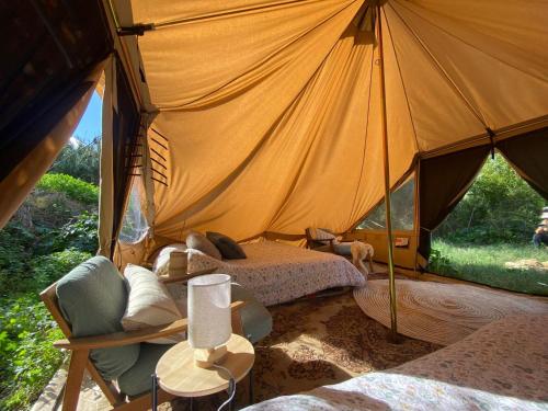a tent with two beds and a chair in a room at Organic Farmstay Glamping in St. Paul's Bay