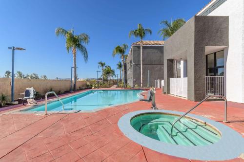 a swimming pool in front of a house with palm trees at Studio 6 Suites Perris, CA in Perris