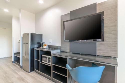 a living room with a tv and a blue chair at Studio 6 Suites Perris, CA in Perris