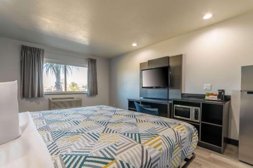 a bedroom with a bed and a flat screen tv at Studio 6 Suites Perris, CA in Perris