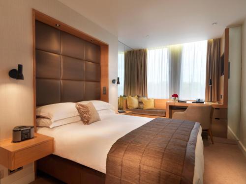 um quarto com uma cama grande e uma secretária em Royal Garden Hotel em Londres