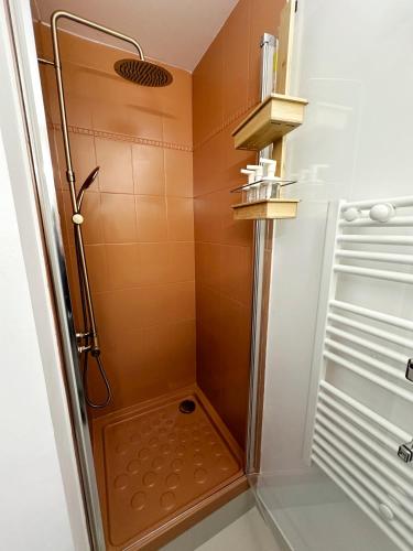 La salle de bains est pourvue d'une douche et d'un mur orange. dans l'établissement La Croix Blanche - Studio Cosy - Place de parking, à Les Sables-dʼOlonne