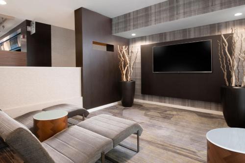 a waiting room with a couch and a tv at Courtyard by Marriott Dallas Plano Parkway at Preston Road in Plano