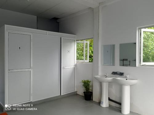 a white bathroom with two sinks and a window at Dream Sun hostel in Weligama