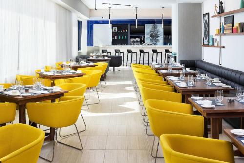 a dining room with yellow chairs and tables at Le Méridien Chicago - Oakbrook Center in Oak Brook